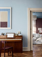 En stue med vægge i den lyseblå farve Jotun 40054 North, listværk i den beige nuance Jotun 12299 Beige Sheen og den brunlilla Jotun 3343 Dusty Purple i baggrunden. Rummet er indrettet med et klaver i træ og en stol.
