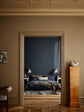 En stue med vægge i brun Jotun 1799 Spice Brown og loft i okkergul Jotun 1909 Kalkoker, med udsigt ind til et soveværelse med en dyb blå væg malet i Jotun 4403 Midnight Blue.