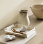 A ceramic vase, tray, and white stones against a wall painted with the colour 1625 Soul from Jotun.