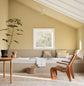 A daybed, wodden chair and a potted plant against muted, greenish yellow walls painted in the colour 1965 Ginger Tea from Jotun. Daybed painted in the colour 12300 Hazelnut Beige. 